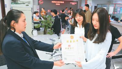 河北省承德市網(wǎng)絡(luò)代購(gòu)經(jīng)營(yíng)者陳晨(右)從工作人員手中接過帶有統(tǒng)一社會(huì)信用代碼的營(yíng)業(yè)執(zhí)照。 劉環(huán)宇攝(人民圖片)