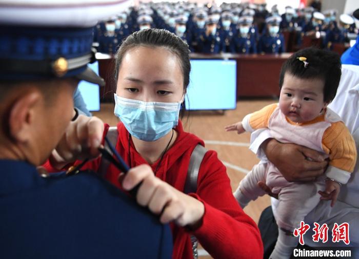 新消防員楊振的妻子彭莉與女兒現(xiàn)場見證丈夫加入“火焰藍”的神圣時刻?！⒅铱?攝